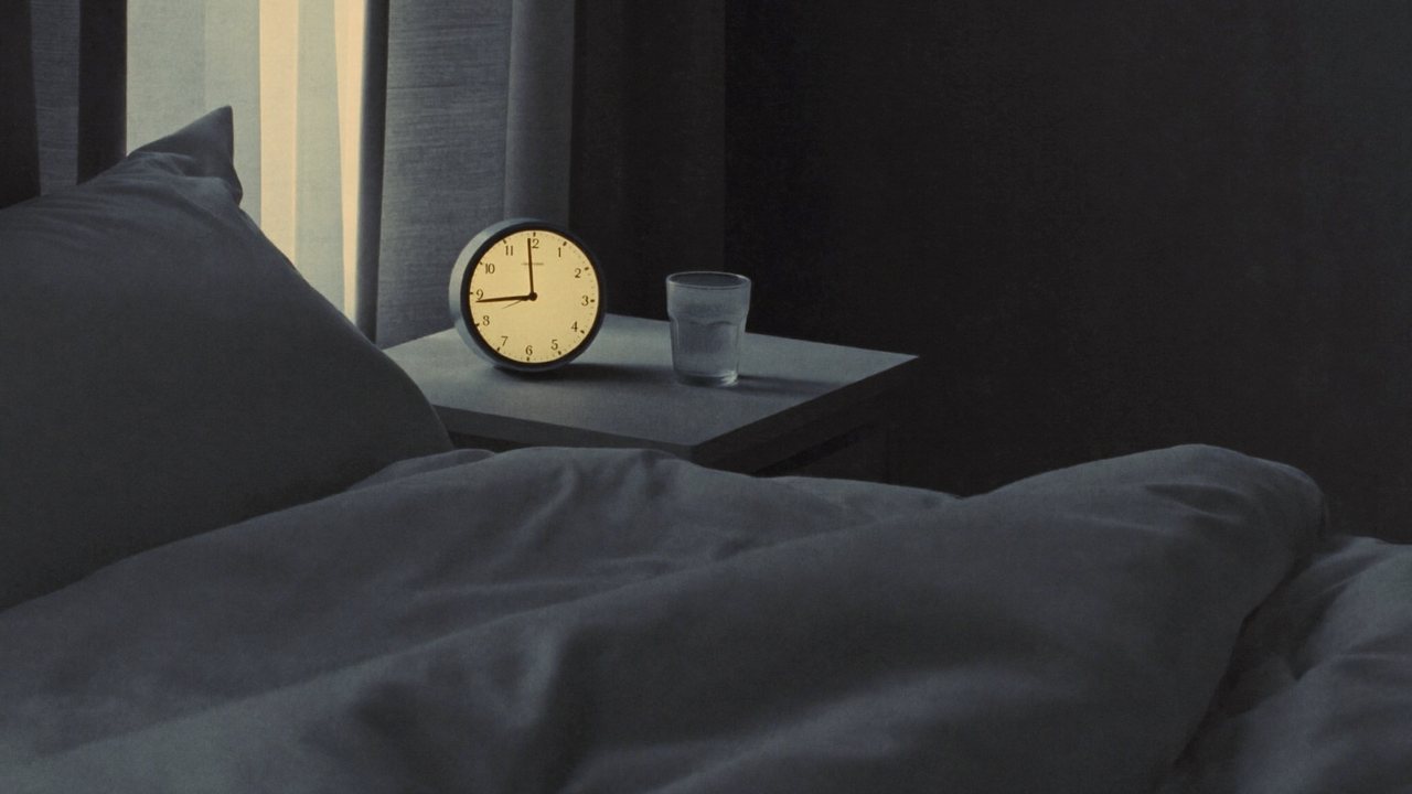 A dim bedroom at 3 a.m. with a softly glowing clock and a glass of water on the nightstand.