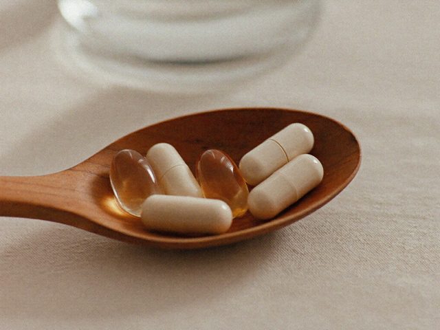 CoQ10 softgel capsules on a wooden spoon